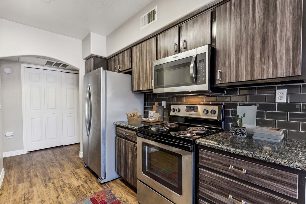 a kitchen with stainless steel appliances and wooden cabinets at Altezza High Desert, Albuquerque